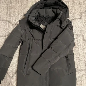 Canada Goose Wyndham (black label) - Helt ny Canada Goose Wyndham i färgen grå med black label. Jackan är i storlek M. Avtagbar päls, påse och väska tillkommer. Kontakta mig för fler frågor!