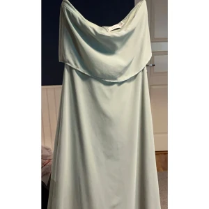 Ljusgrön axelbandslös klänning från Vila - En jätte fin bal/avslutningsklänning med avtagbara axelband och klister på insidan så den sitter fast utan banden. Är 163cm och klänningen var precis vid marken med skor på. Endast använd 1 gång. Priset går att diskutera. Även bättre bilder går att få☺️