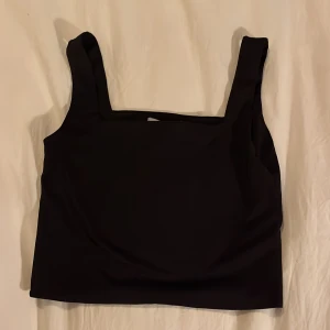 Svart croppad linnetopp - Snygg svart croppad linnetopp med breda axelband. Perfekt för en stilren look.
