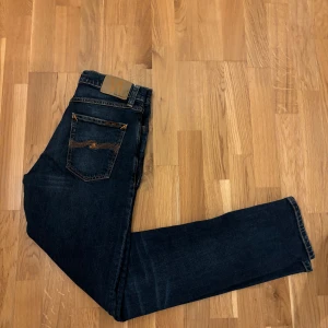 Mörkblå jeans från Nudie Jeans - Säljer ett par snygga mörkblå jeans från Nudie Jeans i storlek W28 L32 Steady Eddie II. Jeansen är i väldigt bra skick inga tecken på användning. Nypris cirka 1500