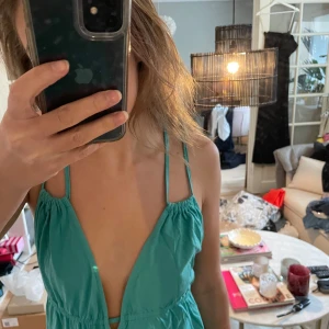 Turkos långklänning med knytband - Säljer en superfin turkos långklänning med smala axelband och knytband i ryggen. Perfekt för sommardagar eller en avslappnad fest. Klänningen har en djup v-ringning och är gjord i ett lätt och luftigt material. Passar perfekt för en bohemisk look!