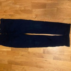 Mörkblå chinos från Hampton Republic - Säljer ett par mörkblå chinos från Hampton Republic i storlek 164. Byxorna har en klassisk stil med knappar och dragkedja framtill. Perfekta för både vardag och lite finare tillfällen. De är i bra skick och redo för en ny ägare!