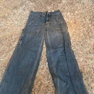Blå cargopants i jeansmaterial - Säljer ett par snygga blå cargopants i jeansmaterial. De har en loose passform med flera praktiska fickor och en cool, avslappnad stil. Perfekta för en casual look eller en dag ute med vänner. Passar till både sneakers och boots!