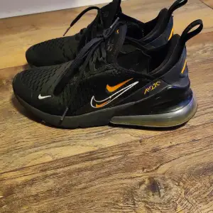 Säljer ett par snygga svarta Nike sneakers i mycket bra skick. De har coola orange detaljer och en luftig design med snörning. Perfekta för både träning och vardag. Storlek EUR 38.5, passar perfekt för dig som vill ha stil och komfort i ett.