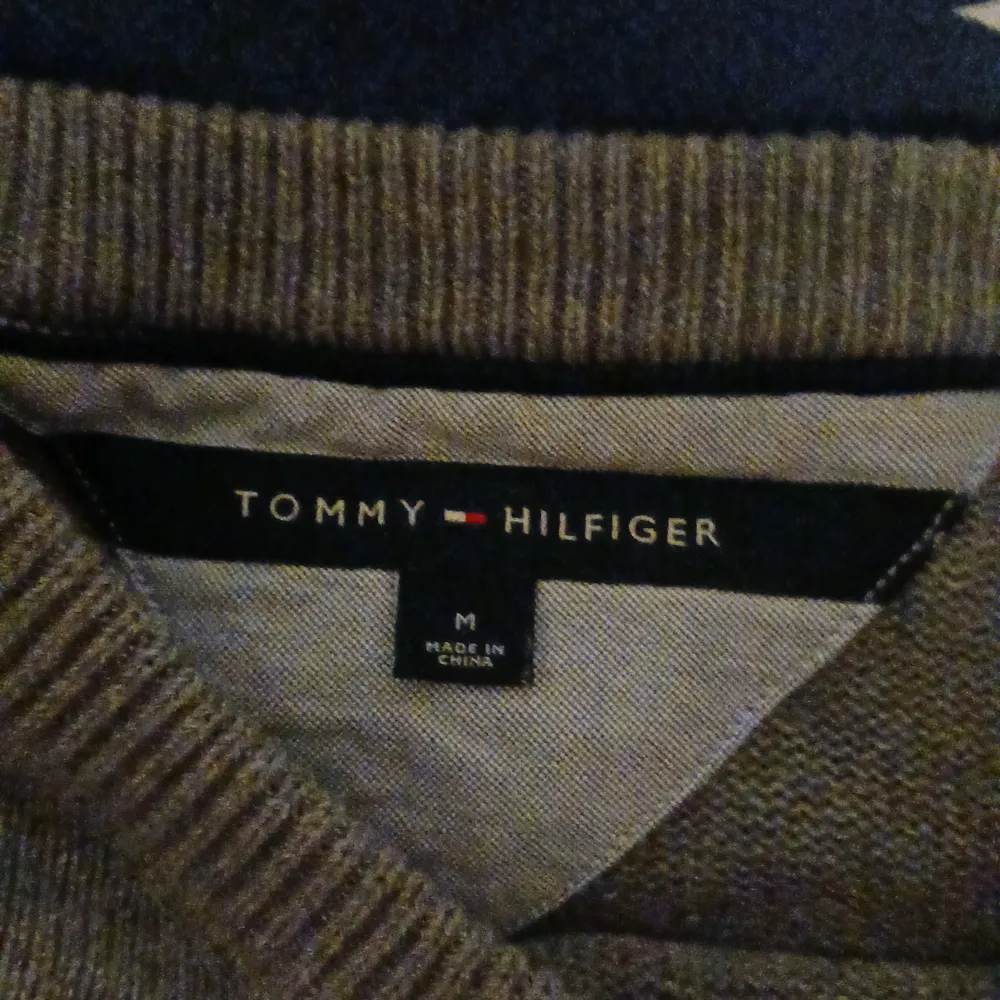 Säljer en stilren grå stickad tröja från Tommy Hilfiger i storlek M. Tröjan har en liten broderad logga på bröstet och är perfekt för både höst och vinter. Den är i mycket bra skick och passar till både vardag och fest. Skön och varm, perfekt för kyliga dagar!. Tröjor & Koftor.