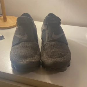Svarta Nike Vapormax i bra skick - Säljer ett par svarta Nike Vapormax i bra skick. De har en stilren design med elastisk överdel och den ikoniska Vapormax-sulan för extra komfort. Perfekta för både träning och vardagsbruk. Passar dig som gillar en modern och sportig look. Kom privat för fler bilder. Ganska små i storlek så passar även dem som har storlek 41.