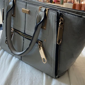 Handväska - Supersnygg blågrå väska från river island🤍 andvänd men fortfarande fin och ej trasig❣️medelstor men precis så man får ner datorn (iaf min dator) ❣️