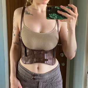 Korsett - Jättefint bälte/korsett i fuskläder, aldrig använd. Har stretch bak och ska passa mellan ca 66-78 cm midja. Säljer även en ljusbrun och en till mörkbrun