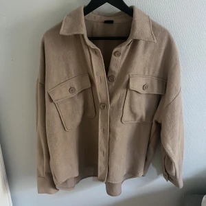 Vår/höstjacka - Fint beige jacka från Gina, använd 1 gång och i bra skick Storlek M Knappar vid ärm-slut  och på framsidan samt 2 fickor på framsidan 