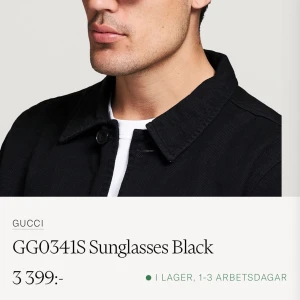 Gucci GG0341S Solglasögon Svart - Snygga och stilrena solglasögon från Gucci, modell GG0341S. De har en klassisk svart färg med en elegant design. Bågarna är dekorerade med Guccis ikoniska ränder i grönt och rött på sidorna, vilket ger en lyxig touch. Perfekta för både vardag och fest!