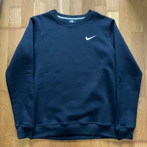 Svart tröja från Nike - Säljer en stilren svart tröja från Nike i storlek S. Den har en enkel design med en vit Nike-logga på bröstet. Perfekt för både vardag och träning. Tröjan är i bra skick och superbekväm!
