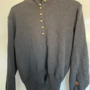 Svart tröja från Busnel - Säljer en klassisk svart tröja från Busnel, tillverkad i Frankrike. Tröjan har långa ärmar och en stilren design med knappar framtill. Perfekt för både vardag och lite finare tillfällen.