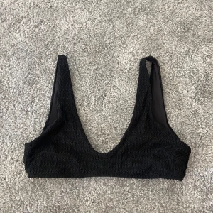 Svart bikiniöverdel från H&M - Säljer en snygg svart bikiniöverdel från H&M i storlek 40Den har en ribbad textur som ger en cool look och är perfekt för sommarens alla badäventyr. Passformen är normal och den är i nyskick. Perfekt för dig som vill ha en stilren och bekväm bikiniöv