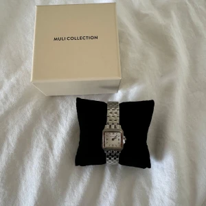 Muli Collection klocka  - Muli Collection klocka i silver som ALDRIG har använts. All skyddsplast är på och den har aldrig använts. 