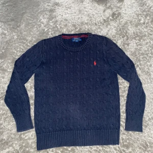 Ralph lauren kabelstickad tröja - Denna snygga Ralph lauren tröja passar perfekt nu till hösten och jag skulle säga att den passar 152-158, Skick 8.5/10 med inget tydligt användande.