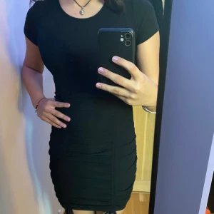 Klänning  - Svart tight klänning med ribb-knyt på låren. Väldigt stretchigt och bekvämt material. Säljer då den inte kommer till användning. Storlek Xs men kan passa större också då den är så stretchig. 