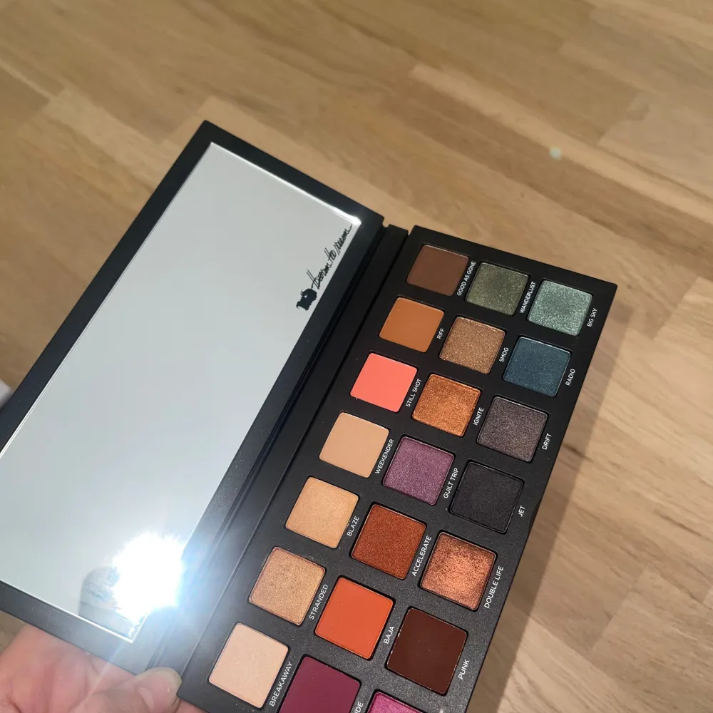 Superfin ögonskuggspalett från Urban Decay med namnet 'Born to Run'. Paletten har en cool design med bilder från olika resmål på utsidan. Inuti finns en stor spegel och 21 olika nyanser av ögonskugga i både matta och skimrande färger.. Skönhet.