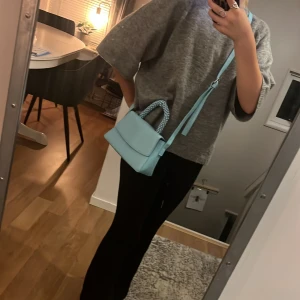 🩵Ljusblå axelväska med pärlhandtag 🩵 - Säljer en superfin ljusblå axelväska med ett unikt pärlhandtag. Väskan är perfekt för både vardag och fest och har en stilren design. Den är gjord i ett syntetmaterial och har en praktisk axelrem för enkel användning. Perfekt för att ge din outfit en färgklick!