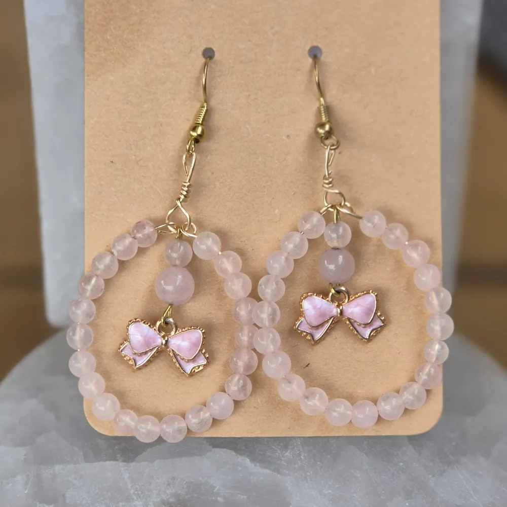 Rosenkvarts Ă€r kĂ€nd som kĂ€rlekens sten och sĂ€gs sprida harmoni och lugn. Den söta rosa rosetten adderar en feminin och lekfull touch, vilket gör dessa örhĂ€ngen till den perfekta accessoaren för att sprida kĂ€rlek och positiv energi i varje outfit. âšđ. Asusteet.