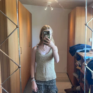 Glittrig guldstickad linne - Säljer en superfin glittrig linne i guld. Den är stickad och har en härlig glans som passar perfekt för festliga tillfällen. Linnet är ärmlöst och har en bekväm passform. Perfekt för att glamma upp vilken outfit som helst! den va mammas men hon gillade inte den. så den passar också vuxna! säljs för att den är för stor men den är i PERFEKT Skick 