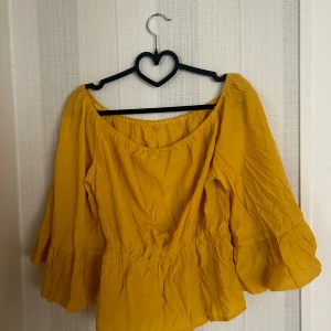 Gul tröja  - Snygg gul off-shoulder topp med volangärmar. Toppen är i en mjuk och skön kvalitet.