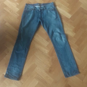 Blå jeans från Acne - Säljer ett par snygga blå jeans från Acne. De är i storlek 34/34 och gjorda av 100% bomull. Jeansen har en klassisk design med fem fickor och en dragkedja. Perfekta för både vardag och fest!