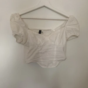 Vit kortärmad topp från H&M Divided - Säljer en söt vit topp från H&M Divided. Den har korta puffärmar och en smickrande passform. Perfekt för sommardagar eller en avslappnad fest. Toppen är i storlek XXS och är i bra skick.