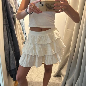 Vit volangkjol - Säljer denna vita kjol nu då den blivit lite för liten! Den är menat att den är högmidjad! - men det går att ta ner den lite på höfterna! Pris går att diskuteras vid snabb affär!