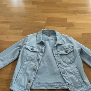 Ljusblå jeansjacka från Sincerely Love - Säljer en snygg ljusblå jeansjacka från Sincerely Love. Jackan har en klassisk design med knappar framtill och två bröstfickor med lock. 