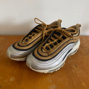 Nike Air Max 97 i guld och silver - Fina skor som inte kommer till användning längre. Använt skick, tex repor på sulan (se närbild). Relativt små till storleken, jag har 38 och kan ha dessa.