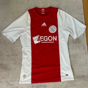 Ajax hemmatröja 2008-2009, storlek S  - Ajax hemmatröja från 2008-2009 med AEGON sponsor   Storlek: S   Finns slitage på trycket men annars i bra skick. 