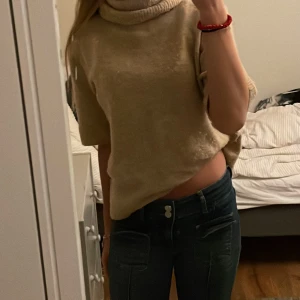 Beige croppad polotröja - Säljer en superfin beige croppad polotröja som är perfekt för höst och vår. Den har en mysig polokrage och korta ärmar, vilket gör den både stilren och bekväm. Passar perfekt till ett par jeans för en avslappnad look. Perfekt för dig som vill ha något unikt i garderoben!