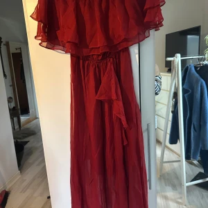 Röd långklänning från Vero Moda - Säljer en elegant röd långklänning från Vero Moda i storlek XS. Klänningen har en vacker volangdetalj upptill och är tillverkad i ett lätt och luftigt material, perfekt för festliga tillfällen. Den har en smickrande passform med resår i midjan för extra komfort. Perfekt för sommarens alla fester! 🌹