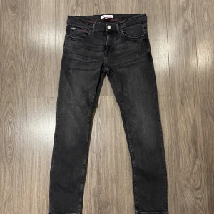 Tommy Hilfiger jeans - Säljer ett par snygga svarta jeans från Tommy Jeans i storlek 32. De har en klassisk femficksdesign och en diskret logga på bakfickan. Perfekta för både vardag och fest! 🖤
