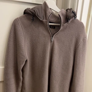 Beige stickad cardigan från Massimo Dutti - Säljer en snygg beige stickad jacka från Massimo Dutti i extrafin ull. Den har en dragkedja framtill och en quiltad luva. Perfekt för höst och vår! Jackan är långärmad och i mycket bra skick. Skriv för fler bilder eller andra frågor. Pris ej hugget i sten 
