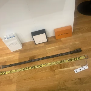 Off-White bälten i svart och gul - Två snygga Off-White bälten till salu! Ett i svart med grå text och ett i gul med svart text 299 kr styck. Båda har den klassiska industriella stilen med metallspänne. Perfekta för att ge din outfit en cool och modern touch. Passar både till vardags och fest!