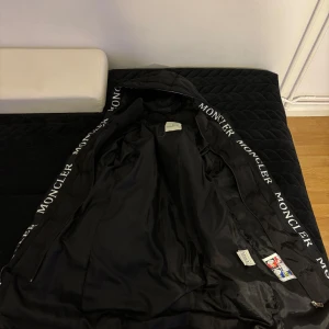 Svart pufferjacka Moncler - Säljer en snygg svart pufferjacka från Moncler i mycket bra skick och knappt använd! Jackan har en dragkedja och Moncler-logga längs ärmarna. Perfekt för kalla dagar med sin varma och vadderade design. Den har en huva för extra skydd mot väder och vind. Storlek M men passar S också😊