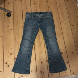 Blå jeans från True Religion - Säljer ett par snygga blå jeans från True Religion i storlek 27. De är uppsydda så passar mig som e 150 cm. Inga defekter, ultra low-waist.De har en bootcut-stil. Perfekta för både vardag och fest! 🕺nypris 1399