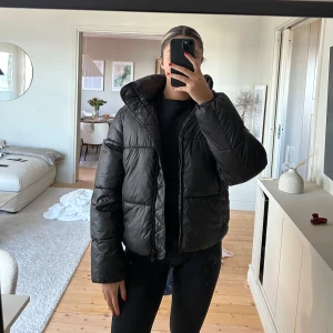 Svart vinterjacka från hm - Säljer en svart pufferjacka i mycket bra skick. Den är perfekt för kalla dagar med sin tjocka vaddering och har en praktisk dragkedja framtill. Jackan har en normal passform och långa ärmar, vilket gör den idealisk för både höst och vinter. Den är både snygg och funktionell!