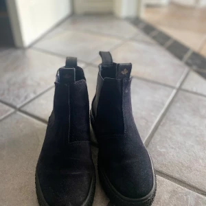 Svarta boots i mocka - Säljer ett par snygga svarta boots i mocka. De har en stilren design med elastiska paneler på sidorna för enkel på- och avtagning. Perfekta för höst och vinter, och de ger en cool touch till vilken outfit som helst
