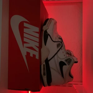 Nike Air sneakers - Säljer ett par klassiska Nike Air sneakers i vitt med svarta och röda detaljer. Skorna har en retro look med den ikoniska Nike-loggan på sidan och AIR-text på hälen. Perfekta för både vardag och träning. De är i bra skick och kommer med originalkartong.