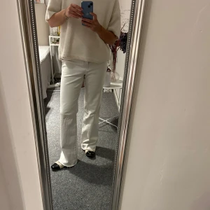 Vita utsvängda byxor CLOSED - Säljer ett par vita byxor i bootcut-stil. De är högmidjade och har en snygg passform som passar perfekt till både vardag och fest. Ett spänne på baksidan. 