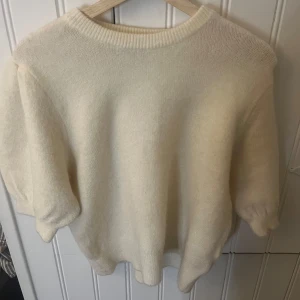 Vit stickad tröja från Gina Tricot - Mysig vit stickad tröja från Gina Tricot i storlek M. Perfekt för kyliga dagar med sin mjuka och varma känsla. Tröjan har en enkel design med ribbad halsringning och trekvartsärmar. Passar både till vardags och lite finare tillfällen.