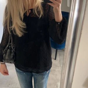 Svart blus med prickigt mönster - Säljer en snygg svart blus från Vero Moda❤️. Blusen har långa ärmar och en knytning vid halsen. Perfekt för både vardag och fest! 
