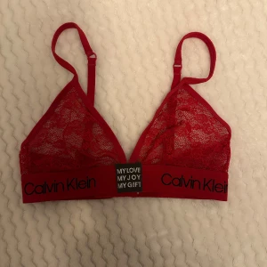 Röd och svart spets-bh  - Två snygga spets-bh:ar från Calvin Klein. Den röda har justerbara axelband och elastiskt band med logga. Den svarta är också i spets med fina detaljer och justerbara band. 60kr styck