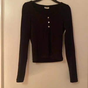 Svart långärmad topp från Vero moda  - Säljer en svart långärmad topp från Vero moda i storlek S. Den har en rund halsringning och tre knappar framtill. Perfekt för både vardag och fest! 🖤