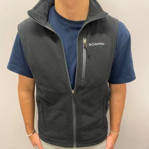 Svart fleeceväst från Columbia - Säljer en svart fleeceväst från Columbia i mycket bra skick. Västen har en dragkedja framtill och en praktisk bröstficka med dragkedja. Perfekt för lager-på-lager under höst och vår. Skön och varm för kyliga dagar!
