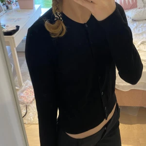 Kofta - Säljer en klassisk svart kofta från H&M i storlek S. Den är i bra skick och har knappar hela vägen ner. Perfekt för både vardag och festliga tillfällen. Passar till allt och är superbekväm! Har dock ett litet hål i nacken men det syns knappt 