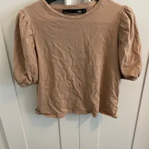 Säljer en söt beige topp från 157 med puffiga kortärmar. Perfekt för både vardag och festliga tillfällen. Toppen är i ett mjukt material och har en rund halsringning. Passar bra till jeans eller kjol för en avslappnad look.