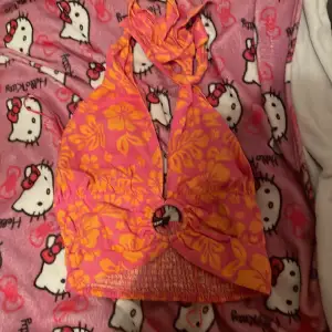 Säljer en superfin topp från BikBok i storlek M men passar som s eller xs. Den är rosa med ett härligt orange blommönster och har en snygg knytning i nacken. Perfekt för sommarens stranddagar! 🏖️